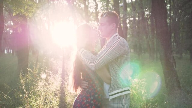 happy and joyful young man and woman embrace in Park in summer at sunset. sun glare in frame. concept of relationship