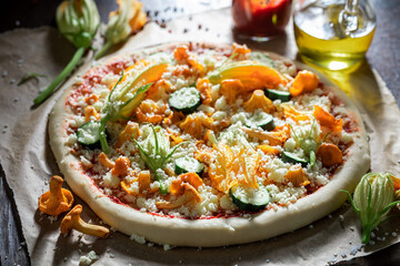 Preparations for vegetarian pizza with chanterelles, zucchini and mozzarella