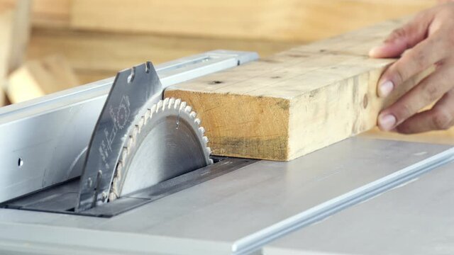 Close-up man hand carpenter sawing wooden with electric saw table machine for make equipment of furniture, Manufacturing industry and repair woodwork, Professional wood handyman use saw slicing timber