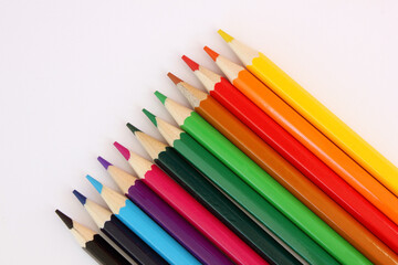 Colored pencils on white background. Many different colored pencils. Color pencil. Pencils are sharp. The pencils placed diagonally in lower right corner. Close-up. Copy space. Background. Flat lay