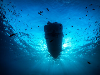 Underwater view of a anchored diving boat against sunlight