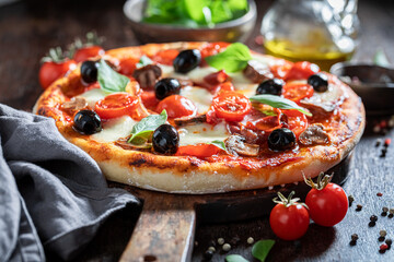 Homemade pizza Capricciosa with mozzarella, prosciutto and tomatoes