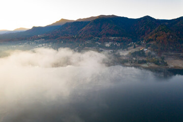 Lovely autumnal landscape with fog over the lake.