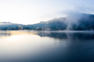 Lovely autumnal landscape with fog over the lake.