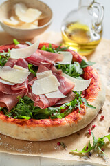 Homemade pizza Parma made of parmesan, prosciutto ham and arugula
