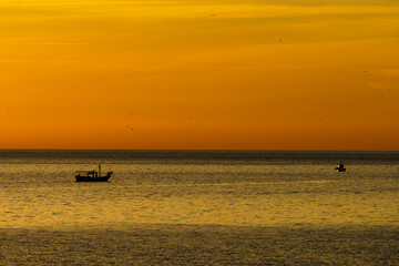 Naklejka premium Fishing boat on sea at sunrise