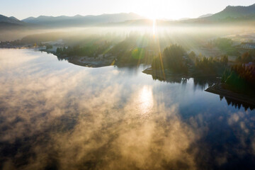 Lovely autumnal landscape with fog over the lake.