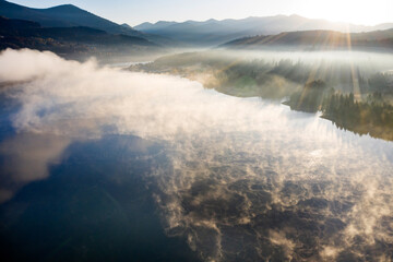 Lovely autumnal landscape with fog over the lake.