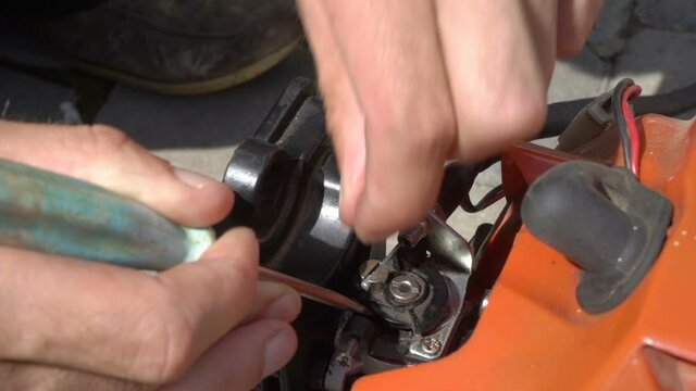 man repairs a trimmer,the mechanic repairs the carburetor of the lawn mower