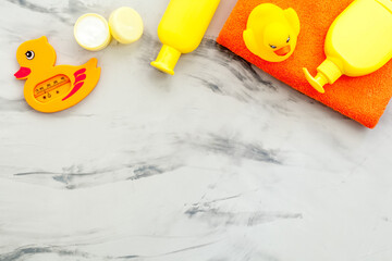 Obraz premium Bath cosmetics and Toy for child. Shampoo, gel, cream, soap and towel. Gray stone background top view