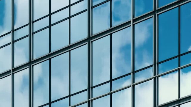 Time lapse of blue sky and clouds reflected in structural modular glass wall. Tilt shot.