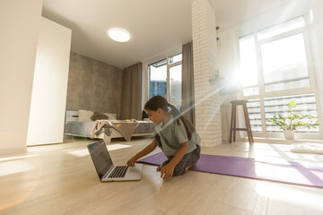 Fototapeta na wymiar Little girl doing her homework at home and using a laptop
