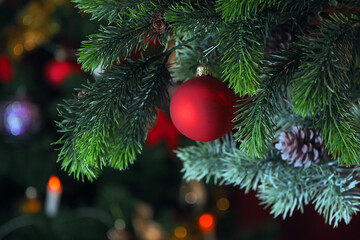 Obraz na płótnie Canvas Christmas decoration on a Christmas tree branch with cones. Red Christmas ball on a Christmas tree. Christmas background
