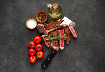 grill t-bone steak with ingredients on a meat knife on stone background