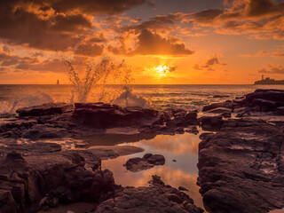 Golden Seaside Sunrise with Boat and Waves Crashing on Rocks