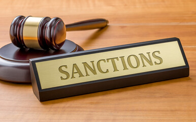 A gavel and a name plate with the engraving Sanctions