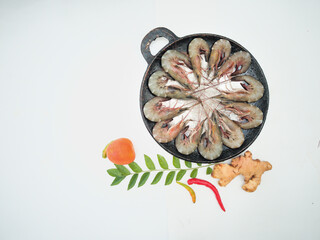 Top view of fresh prawns on a black plate,along with tomato, ginger and curry leaves selective focus.white background.