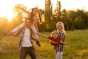Happy family walking in field and looking at sunset