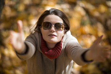 girl in sunglasses in the autumn forest stretches her hands up, with love, top view