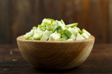 Sliced zucchini in a bowl on a wooden background. Vegetable, ingredient and staple food.