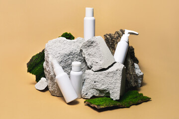 Cosmetic sample white bottle set on stone, moss, wooden podium on bright beige background. Modern...