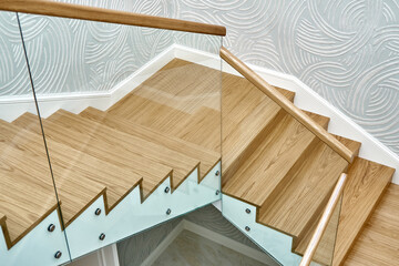 Wooden staircase with glass railings and wooden handrail - obrazy, fototapety, plakaty