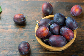 Fresh plums in a wooden bowl. Harvesting.