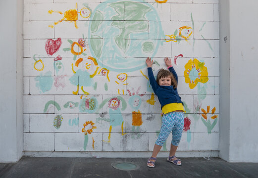 Little girl playing next to a hand-painted mural