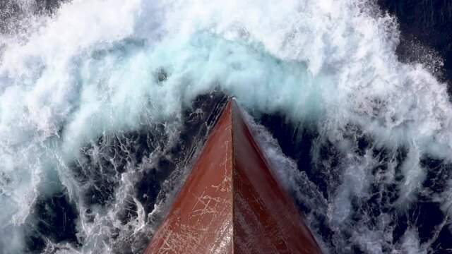 Red bow of a cargo ship breaking the waves.
