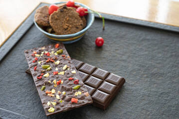 Chocolate bars handmade with strawberries and pistachios on a black background. Craft vegan chocolate