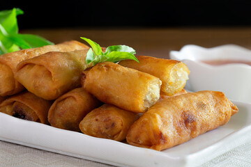 Fried Spring rolls on white dish with sweet suace in the white bowl