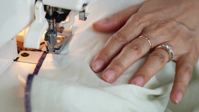 Overlock sewing machine closeup. Asian Seamstress hands.