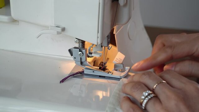 Overlock sewing machine closeup. Asian Seamstress hands.