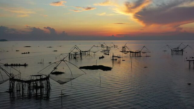 4K drone footage of pakpra fisherman village and traditional fishing net made by bamboo in sea with tourism boat sightseeing in morning located in Phatthalung province Thailand