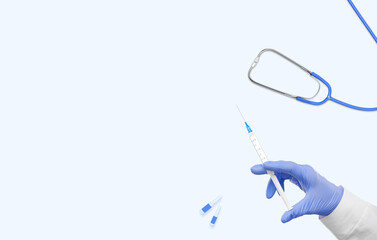 Hand in a blue glove holding syringe and medical devices