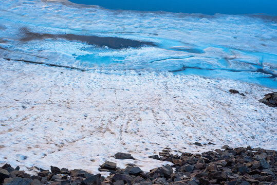 détail d'un lac gelé avec différentes structures de glace et des nuances de bleu 