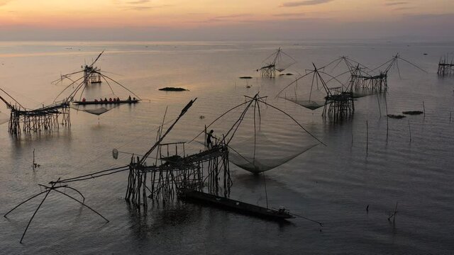 4K drone footage of pakpra fisherman village and traditional fishing net made by bamboo in sea with tourism boat sightseeing in morning located in Phatthalung province Thailand