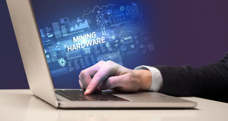 Businessman working on laptop with MINING HARDWARE inscription, cyber technology concept