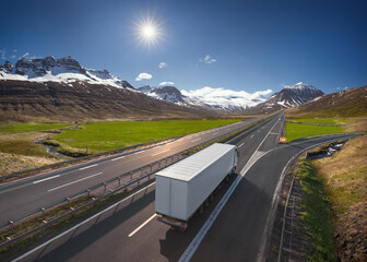 White cargo truck on the asphalt road in beautiful landscape at sunny day