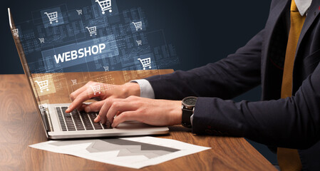Obraz na płótnie Canvas Businessman working on laptop with WEBSHOP inscription, online shopping concept