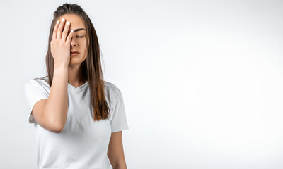 Young woman covers face, feels fatigue, needs good rest, has sleepy expression. Weariness and...