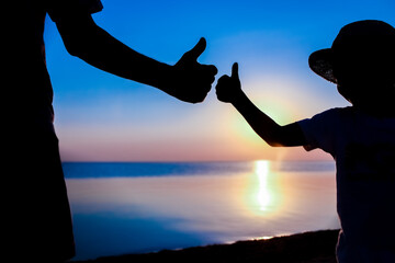 A Hands of happy father and child by the sea on nature silhouette travel