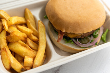 Cheeseburger with freshly made fries ordered for take away or to be delivered home