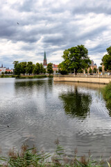 Fototapeta premium Widok na Burgsee z ogrodu zamkowego przy zamku Schwerin w kierunku Kolumny Zwycięstwa, centrum miasta i katedry w Schwerinie w sierpniu 2020 r.