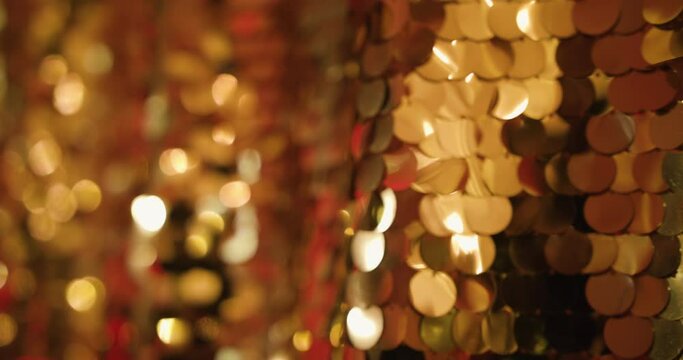 Festive gold fabric texture with shiny particles close up. Beautiful shiny golden background of sequins and bokeh