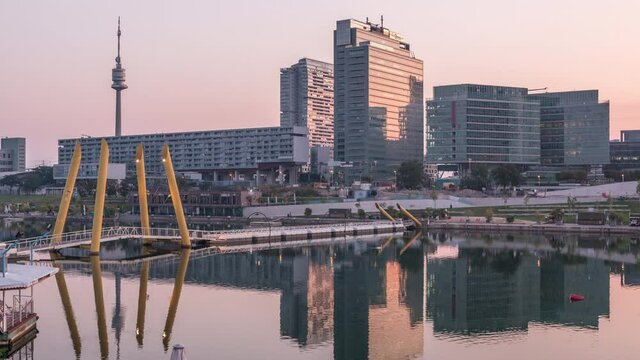 Donaustadt Danube City night to day transition timelapse is a modern quarter with skyscrapers and business centres in Vienna, Austria. Modern architecture and pedestrian bridge illuminated at morning