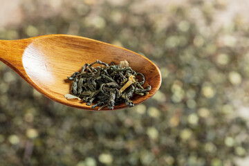Fototapeta na wymiar green tea with jasmine flowers in a wooden spoon on tea background