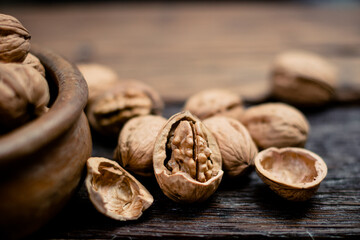 still life with Walnut kernels and whole walnuts on rustic old wooden table