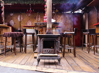 Ancient cast iron stove in the bar of the Christmas market. Front view of the stove with smoke...