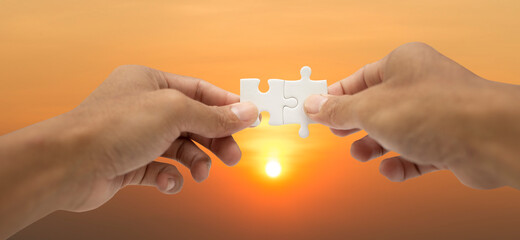 Teamwork  and partnership concept with hands holding jigsaw puzzle to joining success with sunrise background,  